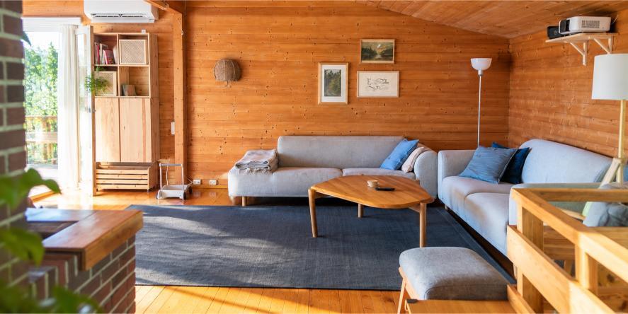 Rengjort stue med trepanel, sofaer og salongbord.